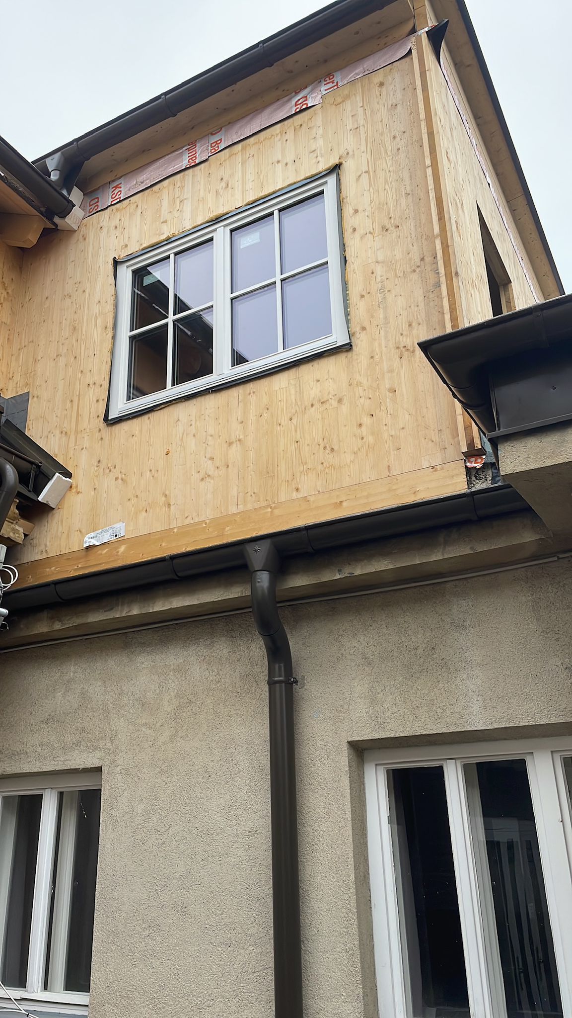 Weißes Sprossenfenster in Holzfassade